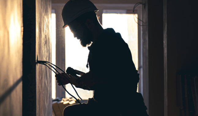 Worker is cutting wires with lineman's pliers.